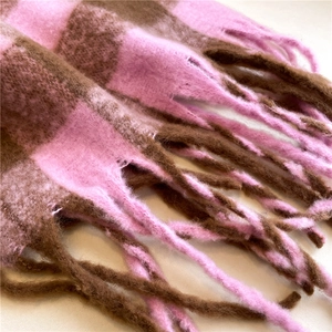 Detailed view of the soft plaid cashmere scarf fabric with elegant pink and brown tassels