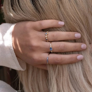 Detailed view of three-piece gold rings with blue sapphires worn on model hand