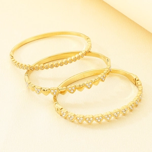Detailed view of three-piece set heart-shaped gold bracelets with sparkling crystals