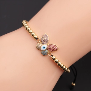 Detailed shot of a gold butterfly bracelet with zircon stones and evil eye on wrist