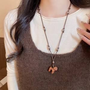 Vue détaillée d'un pendentif caniche en résine marron sur un collier en cordon tressé