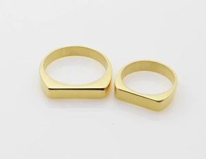 Close-up of gold polished titanium steel signet rings with a flat mirror finish surface