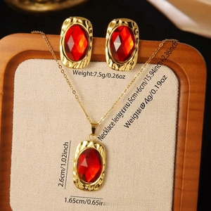 Close-up of vintage jewelry set featuring red faceted gemstones and textured gold borders