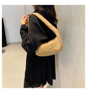 Detail of beige quilted shoulder bag with 3D floral texture on a black blazer