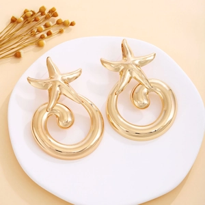Detail of golden starfish earrings with spiral design and polished metallic finish