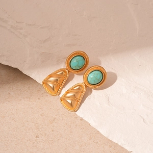 Detail of vintage gold earrings with relief texture and oval turquoise gemstone inlay