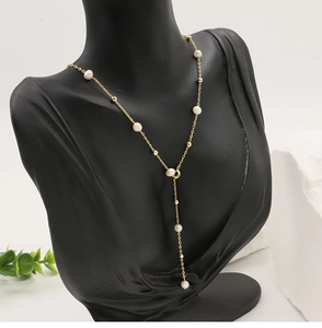 Detail of a gold-plated Y-shaped necklace with natural freshwater pearls on a black bust