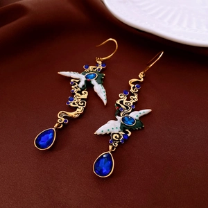 Detailed view of crane earrings with blue gemstone and waterdrop pendant on silk