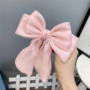 Macro shot of large pink mermaid-style satin bow hair clip with shimmering pearl texture