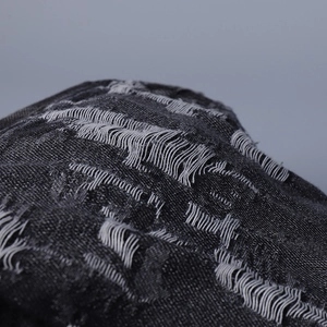 Macro shot of distressed dark grey denim fabric with vintage frayed texture details