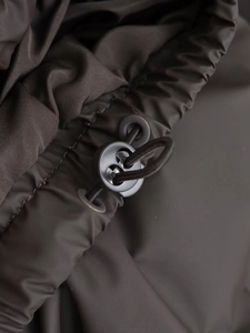 Macro shot of adjustable drawstring toggle and metal eyelet on brown quilted vest fabric