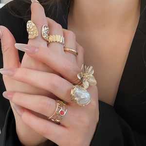 Close-up of gold starfish and baroque pearl rings worn on hand against black blazer