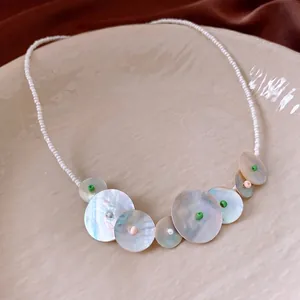 Minimalist white seed bead necklace with circular seashell pendants for beach style