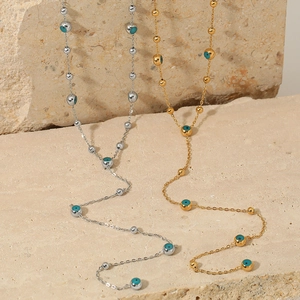 Gold and silver Y-shaped stainless steel necklaces with evil eye beads on rock background