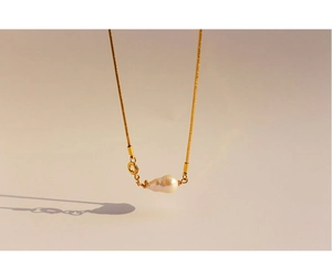 Close-up of golden snake chain with white Baroque pearl pendant and lobster clasp
