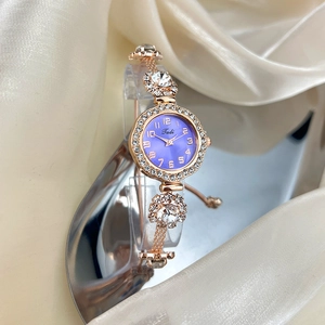 Detail of rose gold quartz watch with purple dial and crystal bezel on velvet