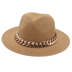 Détail macro d'un chapeau Panama en paille kaki orné d'une chaîne décorative en métal doré
