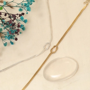 Detail of gold and silver knot pendants on dense snake bone chains with adjustable clasp