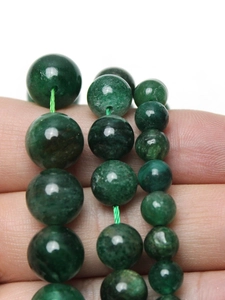Close-up of green fuchsite mica loose beads on fingers showing size and natural texture