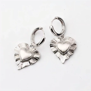 Macro detail of silver heart earrings showing brushed metallic texture and pleated design