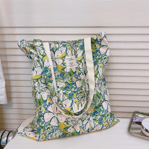 Dettaglio della borsa tote in tela floreale con fiori blu e verdi e manico color crema