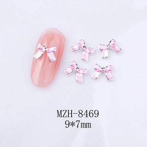 Détail de bijoux d'ongles nœud rose avec bordures en métal argenté taille 9x7mm