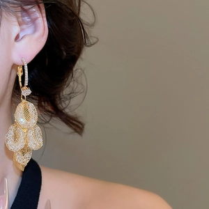 Close-up of golden mesh leaf-shaped long drop earrings with sparkling rhinestones on model
