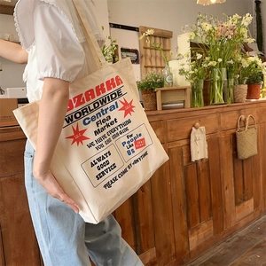 Detail of off-white canvas tote bag with red Zakka print and vintage lettering