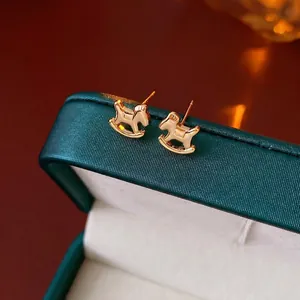 Élégantes boucles d'oreilles cheval à bascule plaquées or sur un écrin de bijoux vert foncé