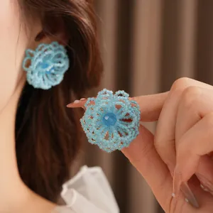 Silver needle woven blue crystal flower stud earrings shown on ear for an elegant style