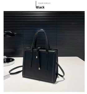 Dettaglio di una borsa tote nera minimalista con finitura liscia e corda in metallo