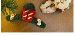 Detail of plush Christmas hair claws featuring festive reindeer and santa claus ornaments