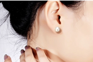 Close-up of a high-quality white freshwater pearl earring on a female model's ear