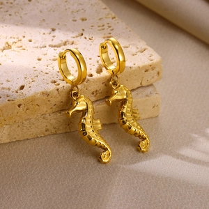 Macro de boucles d'oreilles hippocampe dorées sur pierre avec éclairage naturel doux