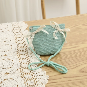 Detail of mint green straw crossbody bag with delicate cream lace bows and zipper closure