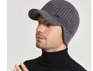 Detail of gray knitted winter visor hat with ear flaps and metallic JEANS logo plaque