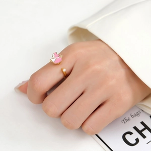 Detailed shot of an adjustable gold ring featuring a pink daisy and a white pearl accent