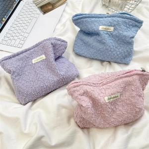 Detailed view of seersucker cosmetic bags in pastel purple, blue and pink with zippers