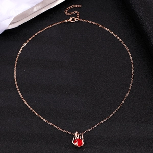 Detailed close-up of a gold chain with flame-style pendant and red gemstone