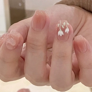 Macro detail of nude pink gradient press-on nails with white camellia flower design