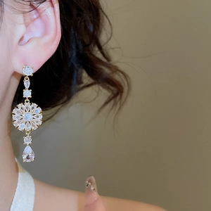 Detailaufnahme eleganter goldener Quastenohrringe mit Zirkonia-Tropfen am Model