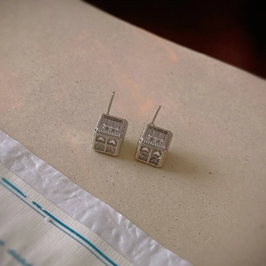 Detail view of geometric cube earrings with letter M engraving and zircon inlay