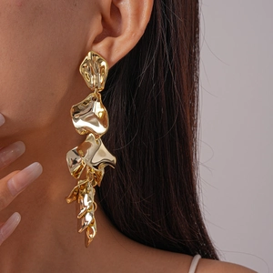Close-up of golden multi-layer metal petal drop earrings worn by a model in detail