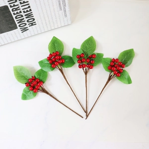 Detailed view of four artificial red berry branches with glossy fruits and green leaves
