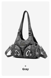 Detailed close-up of gray PU leather handbag with metallic floral charm and multi-pocket zippers