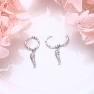 Close-up of S925 silver feather hoop earrings with white zircon on ceramic surface
