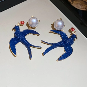 Detail of enamel swallow earrings with red rose and white pearl in gold finish