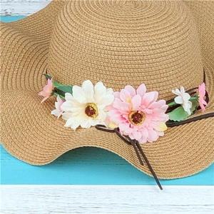 Detailed straw sun hat with pink floral decorations on a nautical wood background