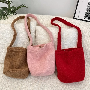 Détail de sacs seaux en peluche marron, rose et rouge avec fermoirs magnétiques en métal