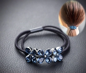 Détail d'un élastique à fleurs en cristal bleu sur cuir noir avec aperçu de coiffure